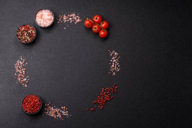 Koyu beton zeminde domates, tuz, baharat ve otlar pişirmek için gerekli malzemeler.