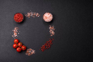 Koyu beton zeminde domates, tuz, baharat ve otlar pişirmek için gerekli malzemeler.