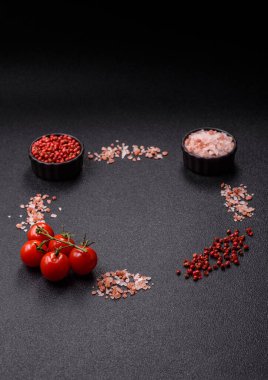 Koyu beton zeminde domates, tuz, baharat ve otlar pişirmek için gerekli malzemeler.