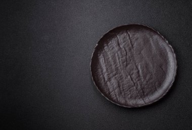 Yemek, risotto ya da makarna için boş yuvarlak siyah tabak yemek masasında mutfak gereçleri. Koyu arkaplanda boş tabak