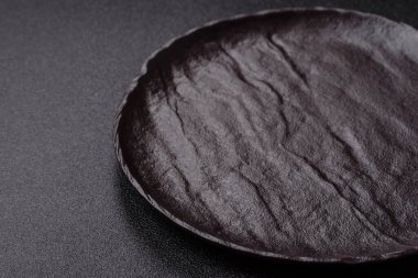 Yemek, risotto ya da makarna için boş yuvarlak siyah tabak yemek masasında mutfak gereçleri. Koyu arkaplanda boş tabak