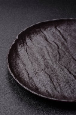 Yemek, risotto ya da makarna için boş yuvarlak siyah tabak yemek masasında mutfak gereçleri. Koyu arkaplanda boş tabak