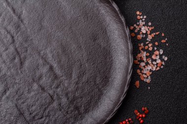 Yemek, risotto ya da makarna için boş yuvarlak siyah tabak yemek masasında mutfak gereçleri. Koyu arkaplanda boş tabak