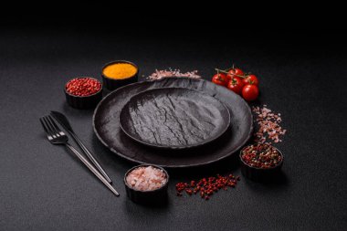 Yemek, risotto ya da makarna için boş yuvarlak siyah tabak yemek masasında mutfak gereçleri. Koyu arkaplanda boş tabak