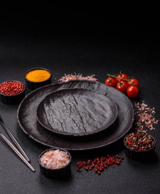 Yemek, risotto ya da makarna için boş yuvarlak siyah tabak yemek masasında mutfak gereçleri. Koyu arkaplanda boş tabak