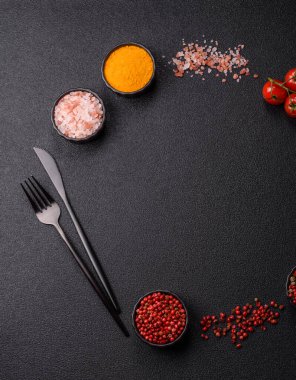 Koyu beton zeminde domates, tuz, baharat ve otlar pişirmek için gerekli malzemeler.