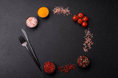 Koyu beton zeminde domates, tuz, baharat ve otlar pişirmek için gerekli malzemeler.