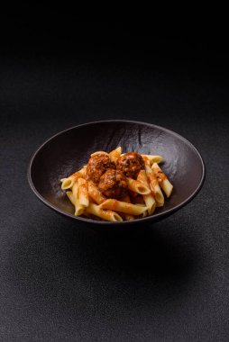 Domates soslu köfteli makarna, tuz ve baharatlı. Koyu beton arka planda İtalyan yemeği makarna