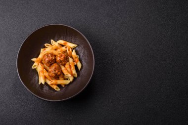 Domates soslu köfteli makarna, tuz ve baharatlı. Koyu beton arka planda İtalyan yemeği makarna