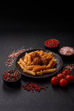 Domates soslu köfteli makarna, tuz ve baharatlı. Koyu beton arka planda İtalyan yemeği makarna
