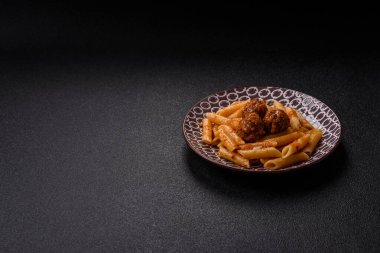 Domates soslu köfteli makarna, tuz ve baharatlı. Koyu beton arka planda İtalyan yemeği makarna