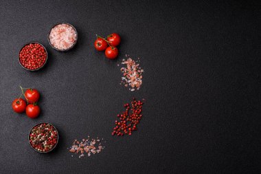 Koyu beton zeminde domates, tuz, baharat ve otlar pişirmek için gerekli malzemeler.