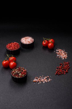 Koyu beton zeminde domates, tuz, baharat ve otlar pişirmek için gerekli malzemeler.