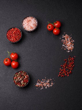 Koyu beton zeminde domates, tuz, baharat ve otlar pişirmek için gerekli malzemeler.