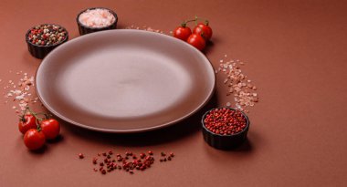 Tek renkli kahverengi arka planda boş seramik plaka. Yemek masasında çatal bıçak takımı olan boş bir tabak.