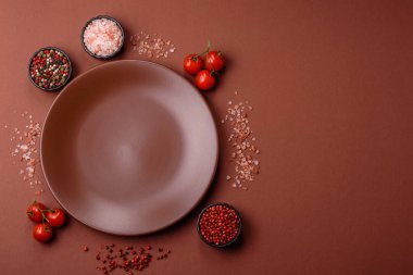 Tek renkli kahverengi arka planda boş seramik plaka. Yemek masasında çatal bıçak takımı olan boş bir tabak.