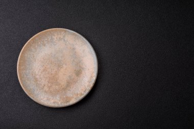 Yemek için boş yuvarlak siyah tabak, yemek masasında mutfak gereçleri. Koyu arkaplanda boş tabak