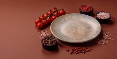 Yemek için boş yuvarlak siyah tabak, yemek masasında mutfak gereçleri. Koyu arkaplanda boş tabak