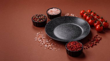 Yemek için boş yuvarlak siyah tabak, yemek masasında mutfak gereçleri. Koyu arkaplanda boş tabak