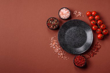 Yemek için boş yuvarlak siyah tabak, yemek masasında mutfak gereçleri. Koyu arkaplanda boş tabak