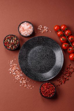 Yemek için boş yuvarlak siyah tabak, yemek masasında mutfak gereçleri. Koyu arkaplanda boş tabak