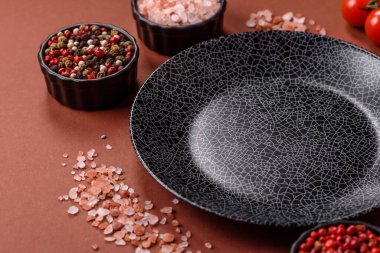 Yemek için boş yuvarlak siyah tabak, yemek masasında mutfak gereçleri. Koyu arkaplanda boş tabak