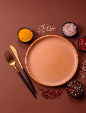 Yemek için boş yuvarlak siyah tabak, yemek masasında mutfak gereçleri. Koyu arkaplanda boş tabak