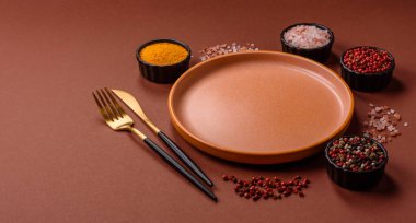 Yemek için boş yuvarlak siyah tabak, yemek masasında mutfak gereçleri. Koyu arkaplanda boş tabak