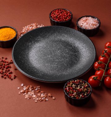 Yemek için boş yuvarlak siyah tabak, yemek masasında mutfak gereçleri. Koyu arkaplanda boş tabak