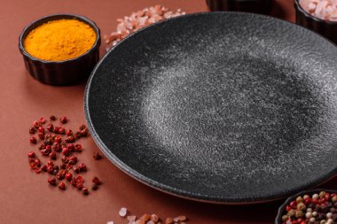 Yemek için boş yuvarlak siyah tabak, yemek masasında mutfak gereçleri. Koyu arkaplanda boş tabak