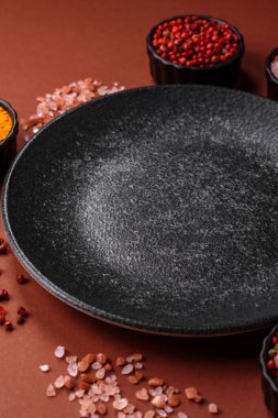 Yemek için boş yuvarlak siyah tabak, yemek masasında mutfak gereçleri. Koyu arkaplanda boş tabak