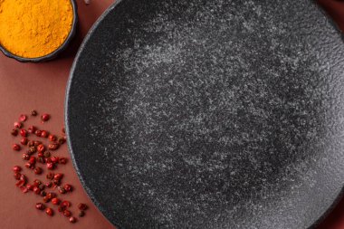 Yemek için boş yuvarlak siyah tabak, yemek masasında mutfak gereçleri. Koyu arkaplanda boş tabak