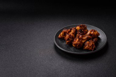 Izgara ya da ızgara tavuk kanadı, teriyaki sosu, baharat ve susam tohumuyla. Koyu arkaplanda tuz ve baharatlı Teriyaki tavuğu