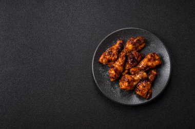 Izgara ya da ızgara tavuk kanadı, teriyaki sosu, baharat ve susam tohumuyla. Koyu arkaplanda tuz ve baharatlı Teriyaki tavuğu