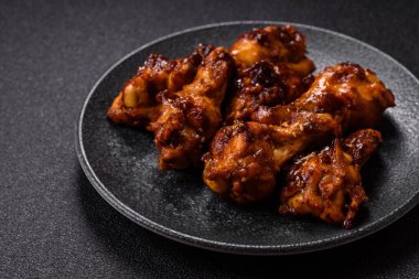 Izgara ya da ızgara tavuk kanadı, teriyaki sosu, baharat ve susam tohumuyla. Koyu arkaplanda tuz ve baharatlı Teriyaki tavuğu