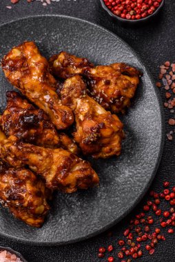 Izgara ya da ızgara tavuk kanadı, teriyaki sosu, baharat ve susam tohumuyla. Koyu arkaplanda tuz ve baharatlı Teriyaki tavuğu