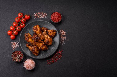 Izgara ya da ızgara tavuk kanadı, teriyaki sosu, baharat ve susam tohumuyla. Koyu arkaplanda tuz ve baharatlı Teriyaki tavuğu