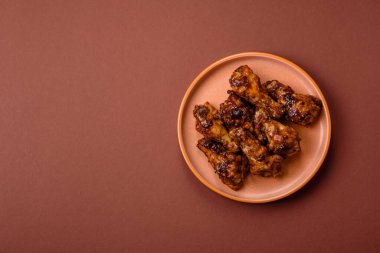 Izgara ya da ızgara tavuk kanadı, teriyaki sosu, baharat ve susam tohumuyla. Koyu arkaplanda tuz ve baharatlı Teriyaki tavuğu