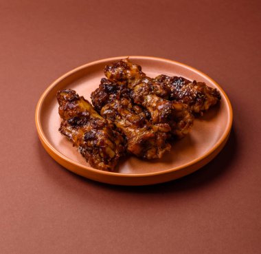 Izgara ya da ızgara tavuk kanadı, teriyaki sosu, baharat ve susam tohumuyla. Koyu arkaplanda tuz ve baharatlı Teriyaki tavuğu