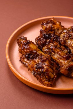 Izgara ya da ızgara tavuk kanadı, teriyaki sosu, baharat ve susam tohumuyla. Koyu arkaplanda tuz ve baharatlı Teriyaki tavuğu