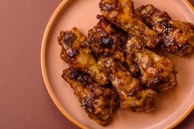 Izgara ya da ızgara tavuk kanadı, teriyaki sosu, baharat ve susam tohumuyla. Koyu arkaplanda tuz ve baharatlı Teriyaki tavuğu