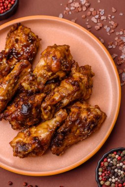 Izgara ya da ızgara tavuk kanadı, teriyaki sosu, baharat ve susam tohumuyla. Koyu arkaplanda tuz ve baharatlı Teriyaki tavuğu