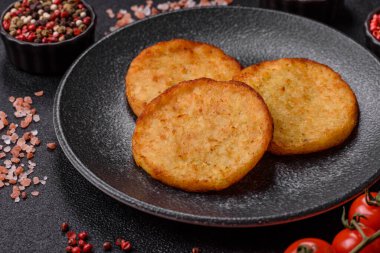 Mücver, patates, soğan ve sebzeden yapılmış kahvaltı yemeği. Koyu beton arka planda patates, tuz ve baharatlı mücver.