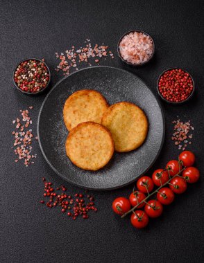 Mücver, patates, soğan ve sebzeden yapılmış kahvaltı yemeği. Koyu beton arka planda patates, tuz ve baharatlı mücver.
