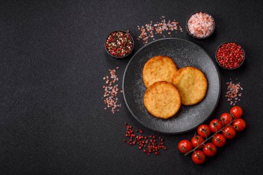 Mücver, patates, soğan ve sebzeden yapılmış kahvaltı yemeği. Koyu beton arka planda patates, tuz ve baharatlı mücver.