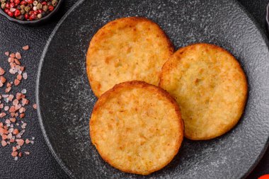 Mücver, patates, soğan ve sebzeden yapılmış kahvaltı yemeği. Koyu beton arka planda patates, tuz ve baharatlı mücver.
