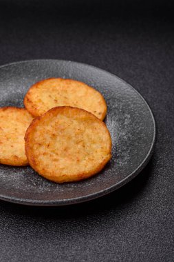 Mücver, patates, soğan ve sebzeden yapılmış kahvaltı yemeği. Koyu beton arka planda patates, tuz ve baharatlı mücver.