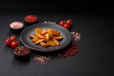 Biberiye, peynir, tuz ve baharatlı ızgara patates dilimleri. Koyu beton zeminde fırında patates dilimleri.