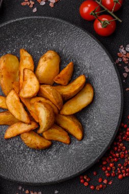 Biberiye, peynir, tuz ve baharatlı ızgara patates dilimleri. Koyu beton zeminde fırında patates dilimleri.