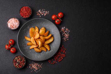 Biberiye, peynir, tuz ve baharatlı ızgara patates dilimleri. Koyu beton zeminde fırında patates dilimleri.